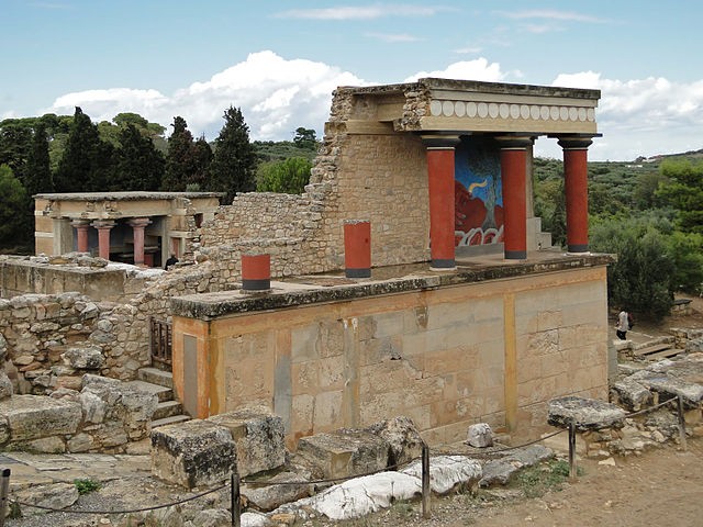 Crumbling wall partly held up by three red pillars