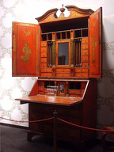 Old desk with open doors revealing drawers and a flat place for writing
