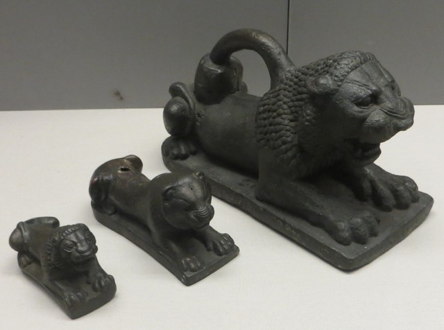 Three dark stone lions on flat platforms